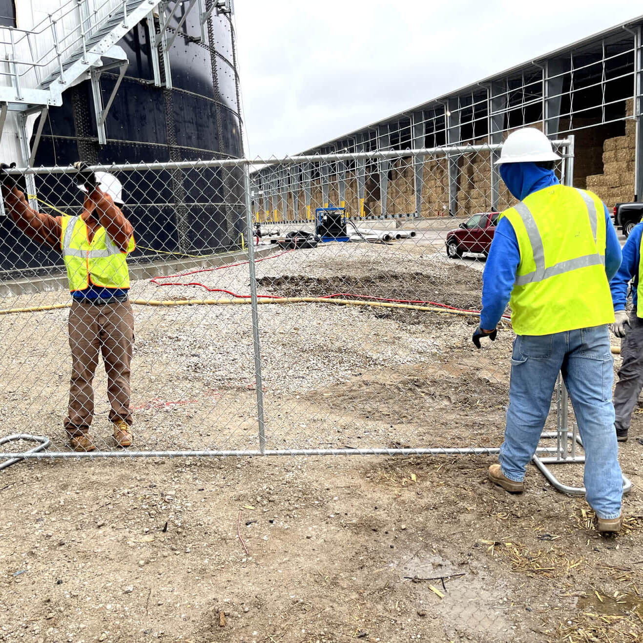 Workers installing temporary fencing around an active construction site.